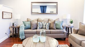Een woonkamer met een bank, twee bijzettafels, een salontafel en een lijst met een afbeelding aan de muur.