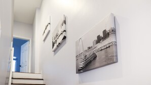 Een gang met drie zwart-witfoto’s aan de muur, waarop een brug en een cruiseschip staan afgebeeld.