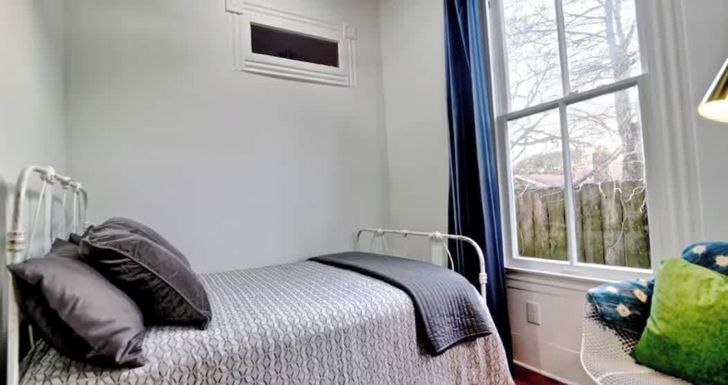 A bedroom with a bed, a window, and a radiator.