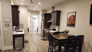 A modern kitchen with dark wooden cabinets, stainless steel appliances, and a dining area with a wooden table and chairs.