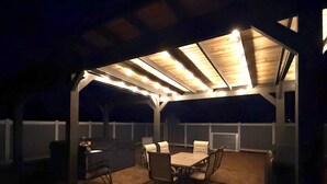 An outdoor patio with a covered seating area, a grill, and a table.