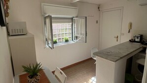 A compact kitchen with a dining area, a window with curtains, and a small island counter.