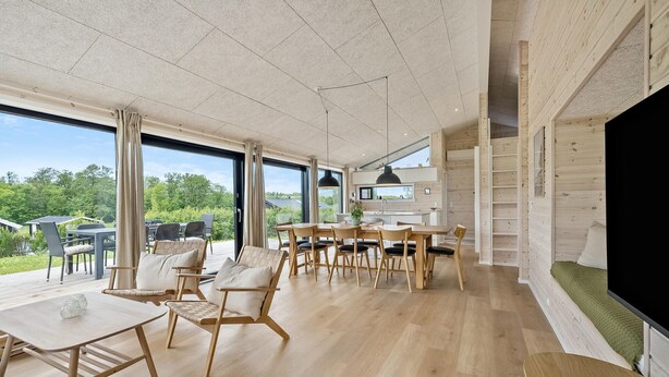 Uma sala de jantar espaçosa com mobiliário de madeira e grandes janelas com vista para o exterior.