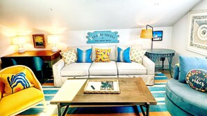 Una sala de estar con un sofá, sillones, una mesa de centro y un tapete estampado.