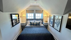 Un dormitorio con cama, dos mesitas de noche, una ventana, una lámpara de techo y un aire acondicionado de pared.