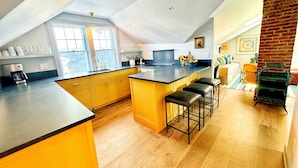 Una cocina moderna con una isla grande, taburetes de bar y vistas al área de estar.