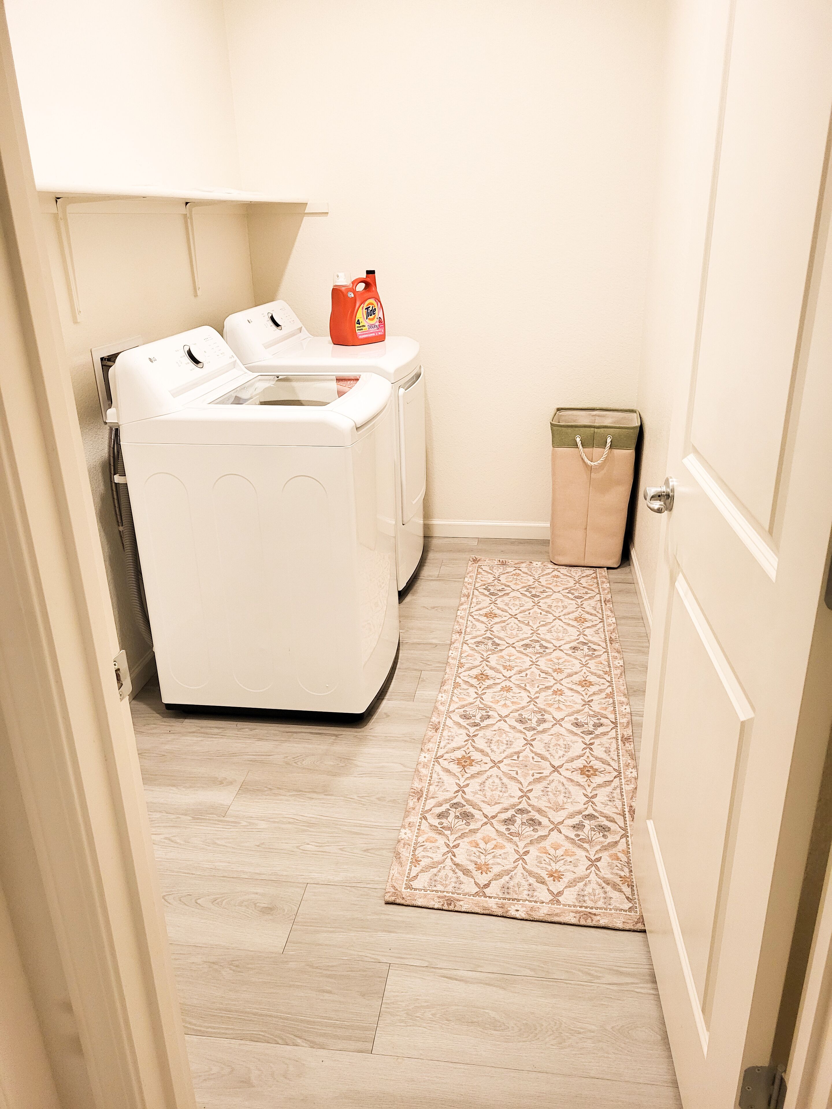 Un cuarto de lavandería con una lavadora, una secadora y una botella de detergente encima.