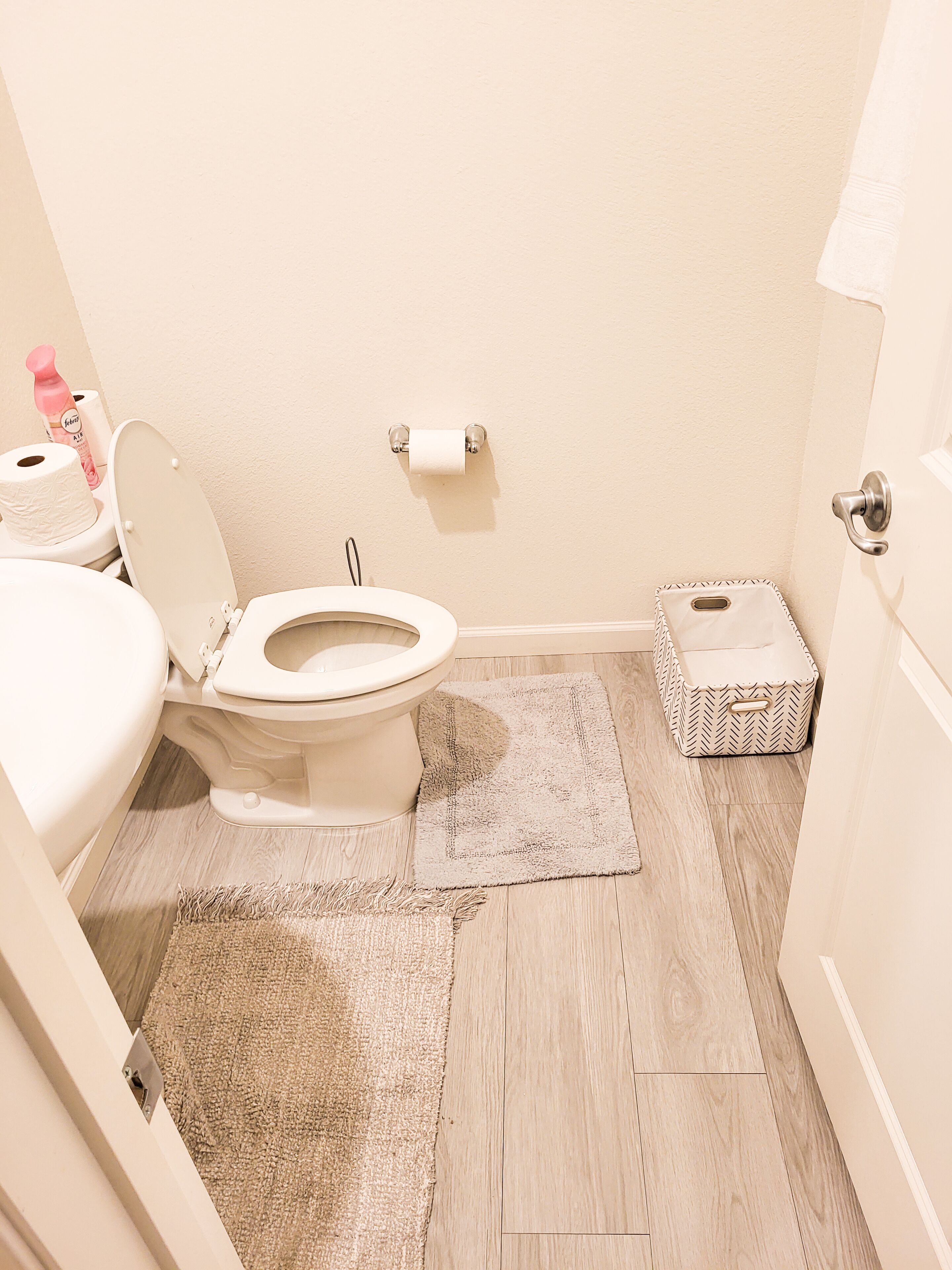 Un bagno piccolo e pulito, con il water, un tappetino e un contenitore portaoggetti.
