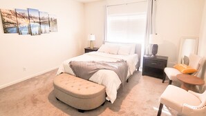 A bedroom with a bed, a nightstand, a chair, a bench, and a wall-mounted picture. - VIP CLASS TWO ~ Real Comfort ~ 3 Bedrooms (Lodi)