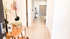 A hallway with a wooden table, potted plants, and a white door. - VIP CLASS TWO ~ Real Comfort ~ 3 Bedrooms (Lodi)