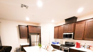 A modern kitchen with dark wooden cabinets, stainless steel appliances, and a large island with stools. - VIP CLASS TWO ~ Real Comfort ~ 3 Bedrooms (Lodi)