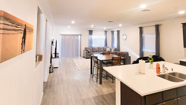 A modern kitchen with a central island, a dining area with a sofa, and a hallway leading to a living room. - VIP CLASS TWO ~ Real Comfort ~ 3 Bedrooms (Lodi)