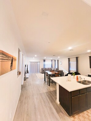 A modern kitchen with a central island, a dining area with a sofa, and a hallway leading to a living room. - VIP CLASS TWO ~ Real Comfort ~ 3 Bedrooms (Lodi)