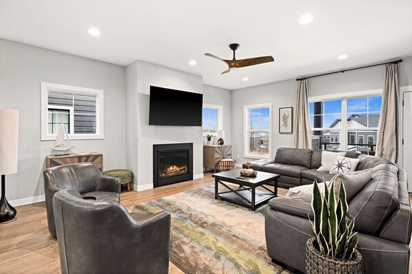 A modern living room with a fireplace, leather sofas, a coffee table, and a flat-screen TV.