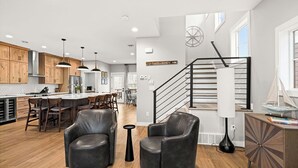 A modern kitchen with wooden cabinets, pendant lights, and a central island with bar stools.