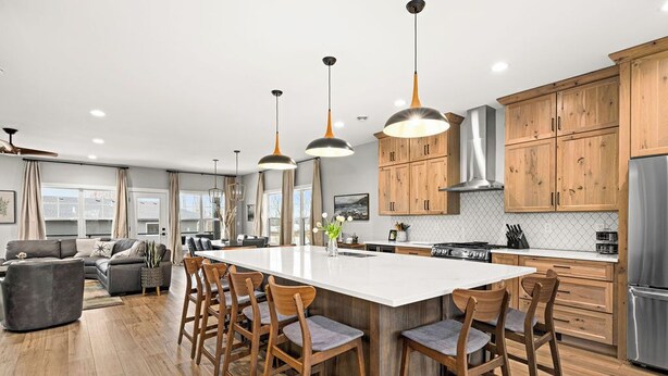 A modern kitchen with wooden cabinets, a large island, and pendant lighting.