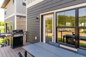 An outdoor patio with a grill, a table, and a sliding glass door leading to a parking area.