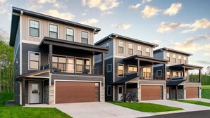 A modern two-story residential building with a garage, a covered outdoor seating area, and a bicycle parked outside.