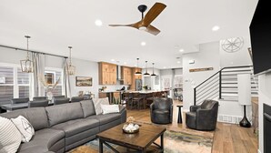 A spacious living room with a gray sectional sofa, a wooden coffee table, and a ceiling fan.