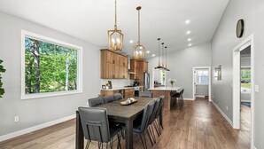 Une cuisine moderne avec des meubles en bois, un grand îlot central et des luminaires suspendus.