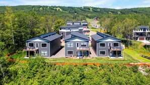 Un complexe résidentiel moderne composé de plusieurs maisons à deux étages, chacune dotée d’un balcon et d’un espace extérieur abrité.