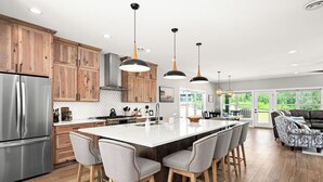 A modern kitchen with wooden cabinets, a stainless steel refrigerator, and a large island with bar stools.