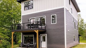 A modern two-story house with a balcony and a covered patio area.