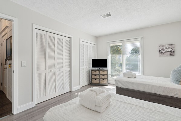 A bedroom with two beds, a television, and a window with blinds. - New Listing! Marsh Views, Pool, and Tennis Courts - 22 Linkside Villa (Isle Of Palms)