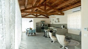 A modern kitchen with a wooden ceiling, a dining area with chairs, and a kitchen island. - Villa Domus Sicilia - Charming Living (Modica)
