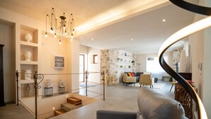 A spacious living area with a staircase, a grey sofa, and decorative shelves. - Villa Domus Sicilia - Charming Living (Modica)