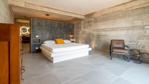 A modern bedroom with a large bed, a chair, and a small table. - Villa Domus Sicilia - Charming Living (Modica)