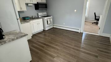 A kitchen with white cabinets, a microwave, stove, and a refrigerator.