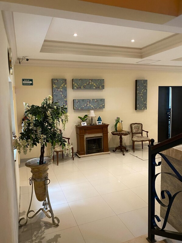 A lobby with a fireplace, floral decorations, and a sign indicating the evacuation route. - Hotel Plaza Express, Torreon Centro (Torreón)
