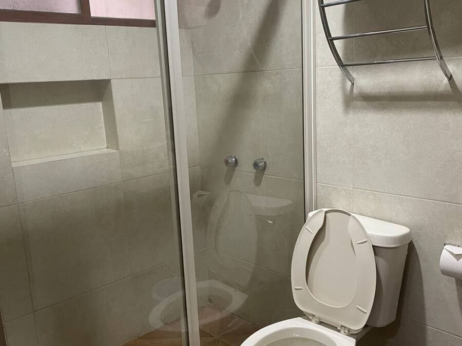 Un baño con ducha acristalada, inodoro y perchero.