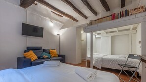 Ein Hotelzimmer mit einem Bett, einer Couch, einem Fernseher und einem Kleiderschrank.