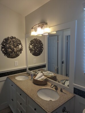 A bathroom with two sinks, a large mirror, and decorative wall art.