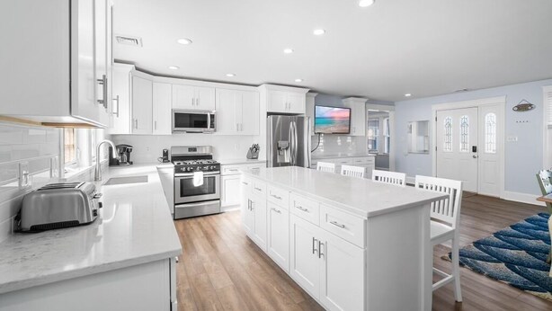 A modern kitchen with white cabinetry, stainless steel appliances, and a central island.