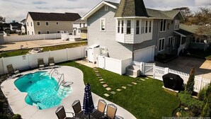 A residential property with a swimming pool, a covered patio, and a large house with a distinctive tower.
