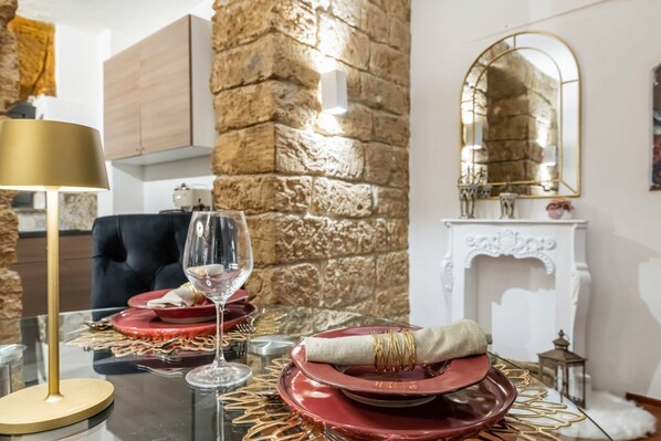 Une table à manger dressée avec des assiettes rouges, un verre à vin et des éléments décoratifs dorés.
