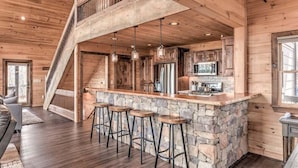 Une cuisine rustique avec un îlot central en pierre, des tabourets de bar et une cuisinière intégrée.