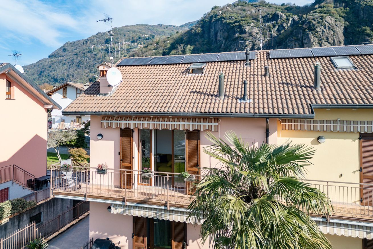 A residential building with a tiled roof, wooden shutters, and a balcony with a railing.