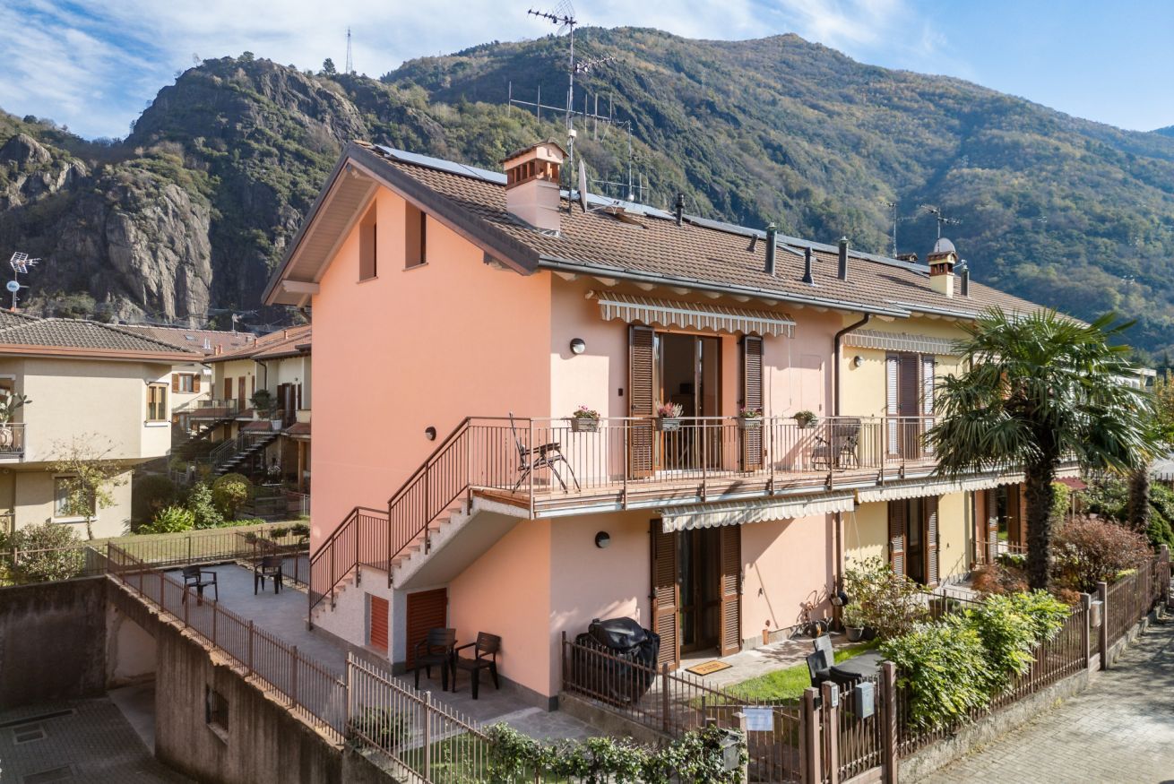 Ein zweistöckiges Gebäude mit Balkon, Treppe und Bergblick.