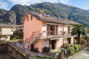 Ein zweistöckiges Gebäude mit Balkon, Treppe und Bergblick.