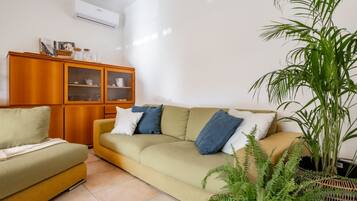 Ein Wohnzimmer mit einer Couch, einem Schrank mit Glastüren und einem Blumentopf.