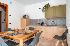 Una cocina compacta con una mesa y sillas de madera, un horno empotrado y un lavamanos pequeño.