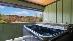 Un jacuzzi en un balcón con vistas a árboles y casas.