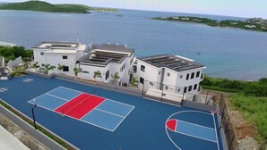 Una cancha de baloncesto al lado de un edificio con vista al mar.