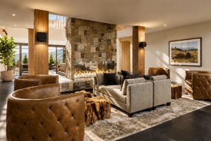 A spacious living area with a stone fireplace, leather sofas, and a large window overlooking a mountainous landscape.