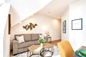 A modern living room with a grey sectional sofa, a coffee table, a side table with a lamp, and a wall art piece.