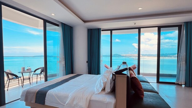 A modern hotel room with a large bed, a sofa, and a balcony with a view of the sea. -  HC HOTEL (Sihanoukville)